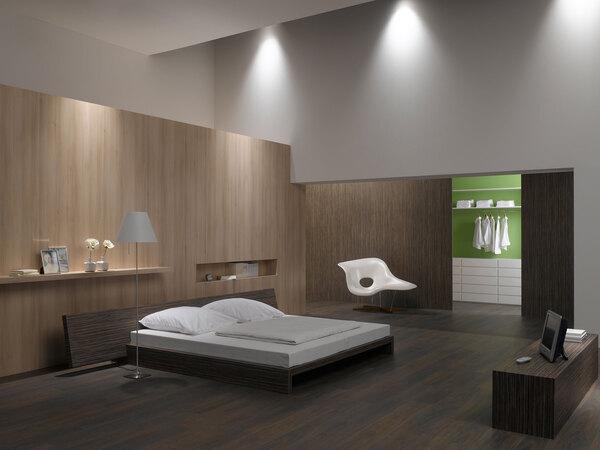 Schlafzimmerimpression mit Holzverkleidung an Wand Schlafzimmerimpression von Bett, Nachtisch und Sideboard mit Holzverkleidung an Wand und indirektert Beleuchtung